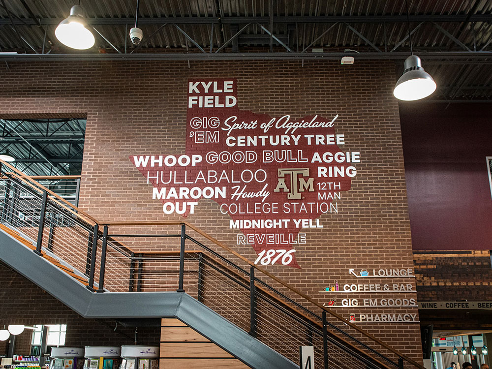 wall art of a maroon texas shape covered in Aggie phrases