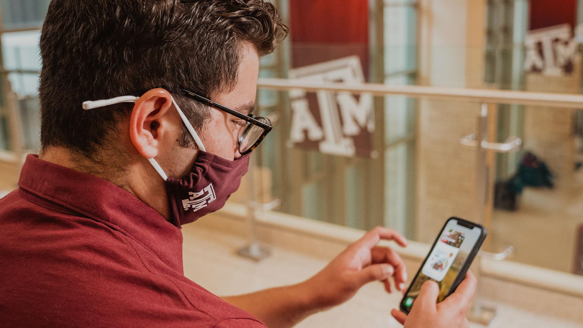 a student uses the HEB app on their smart phone