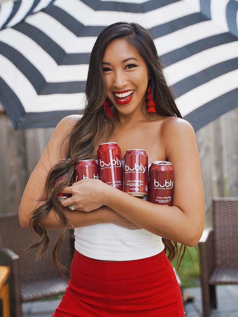 a smiling woman holds multiple cans of bubly in her arms